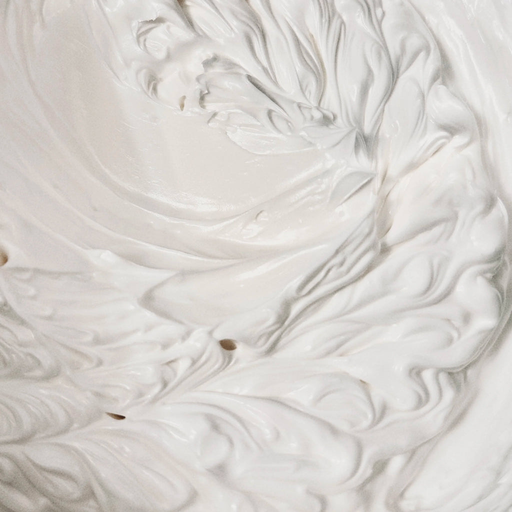 Close-up of white whipped cream with a small brown speck.